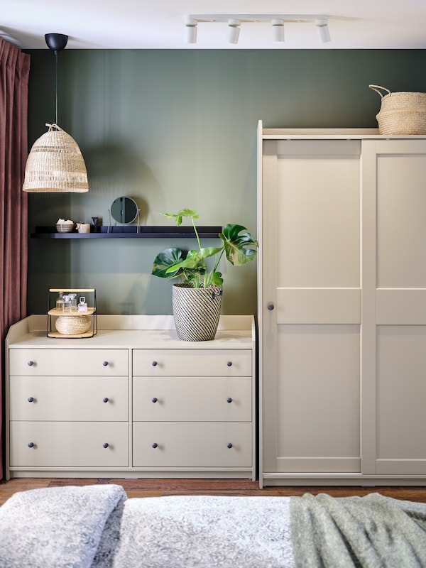 A bedroom with a white HAUGA chest of six drawers beside one HAUGA wardrobe with sliding doors.