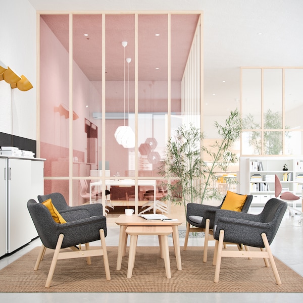 A bright and airy office space with a sitting area comprised of four dark grey VEDBO armchairs and two LISABO coffee tables.