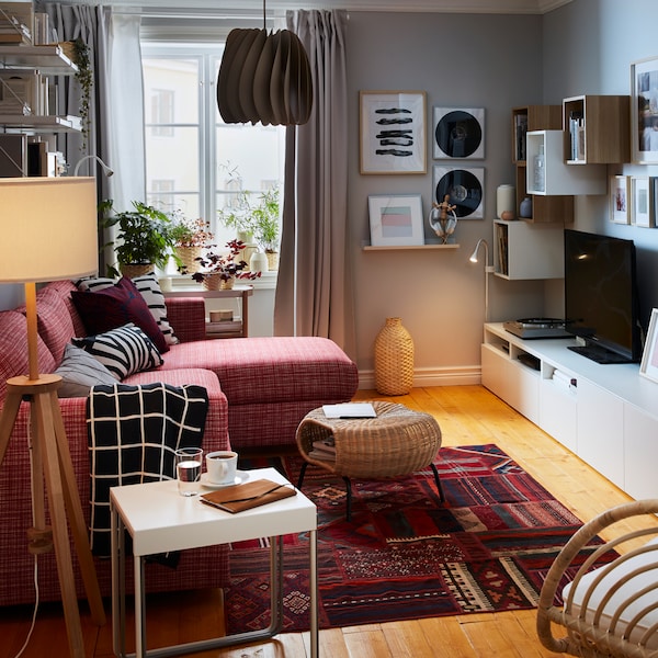 A compact living room with a sofa bed with chaise longue on one side; sideboard, storage, TV, stereo and art on the other.