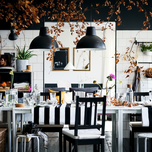 A decorated, black-and-white dining area with brown-black STEFAN chairs and MARIUS stools surrounding two MELLTORP tables.