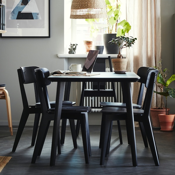 A dining room with a black LISABO table, four black LISABO chairs and a TORARED pendant lampshade.