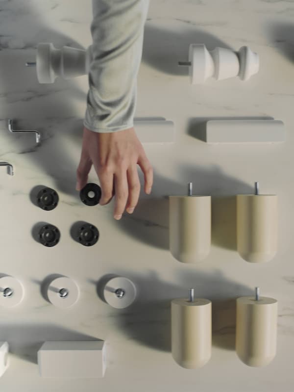 A hand reaching into a neatly arranged display of IKEA spare parts.