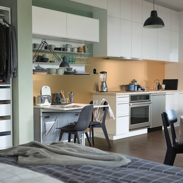 A kitchen area with white SEKTION cabinets, ODGER chairs in anthracite and a SÄLJAN beige stone-effect laminate counter top.