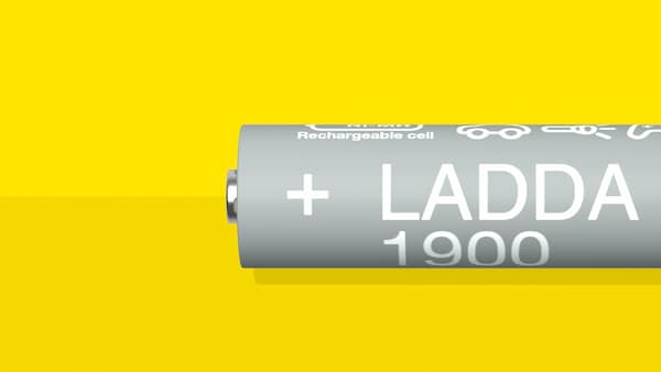 A LADDA rechargeable battery, HR06 AA, with a battery capacity of 1900mAh, is lying on a yellow surface.