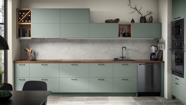 A SEKTION kitchen in white and Bodarp grey-green, with a BARKABODA worktop in walnut veneer and an ESSENTIELL dishwasher.