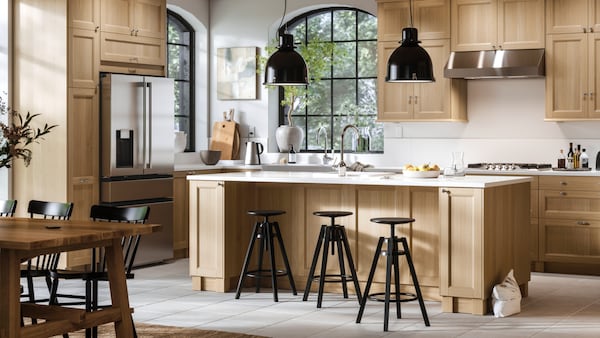 A SEKTION kitchen with a KASKER worktop in white marble effect/quartz, a MÖCKELBY table in oak and NORRARYD chairs in black.