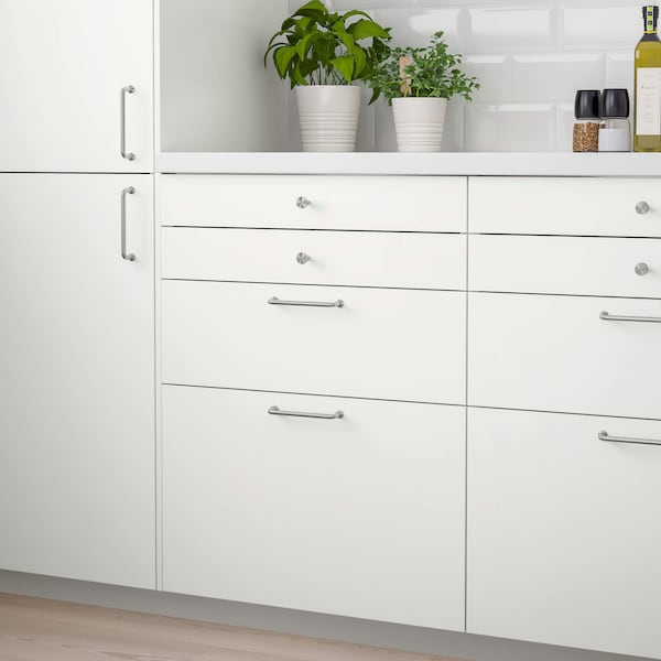 A set of white cabinets with a white countertop and plants sitting on the counter.