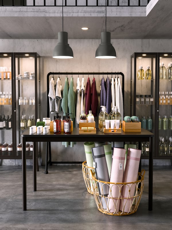 A TOMMARYD table in front of two MILSBO anthracite glass cabinets and a basket of yoga mats on the floor.