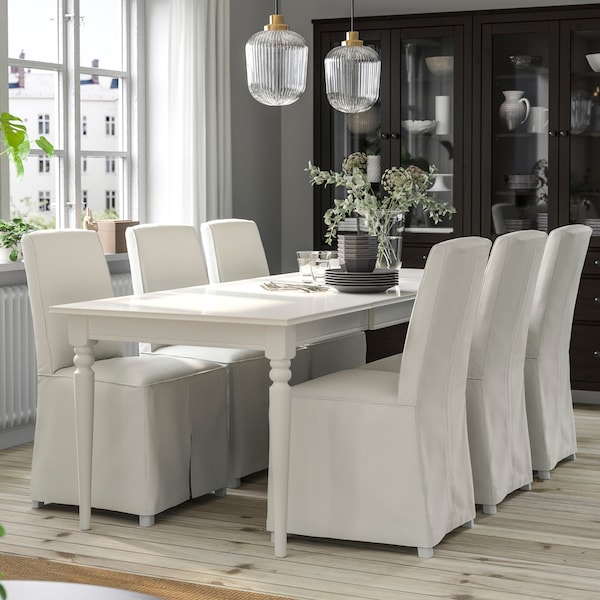 A traditional-style dining room with a white INGATORP table and six white BERGMUND chairs close by a window.