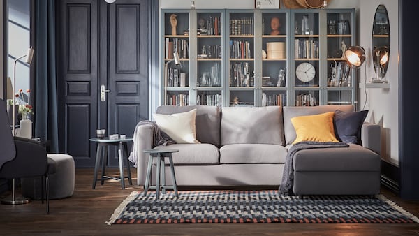 A VIMLE 3-seat sofa with chaise lounge sits partly on a RESENSTAD rug in front of some BILLY bookcases with glass doors.