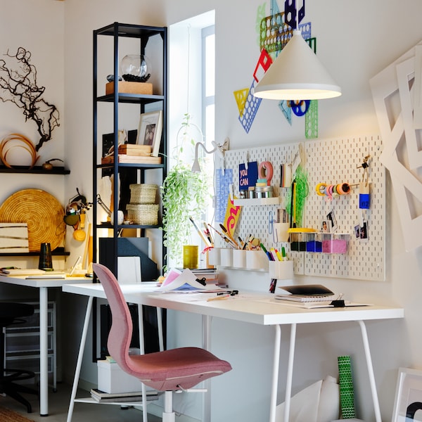 A workspace with a white LAGKAPTEN/TILLSLAG desk, light brown-pink LÅNGFJÄLL office chair, plus white pegboards and pendant.