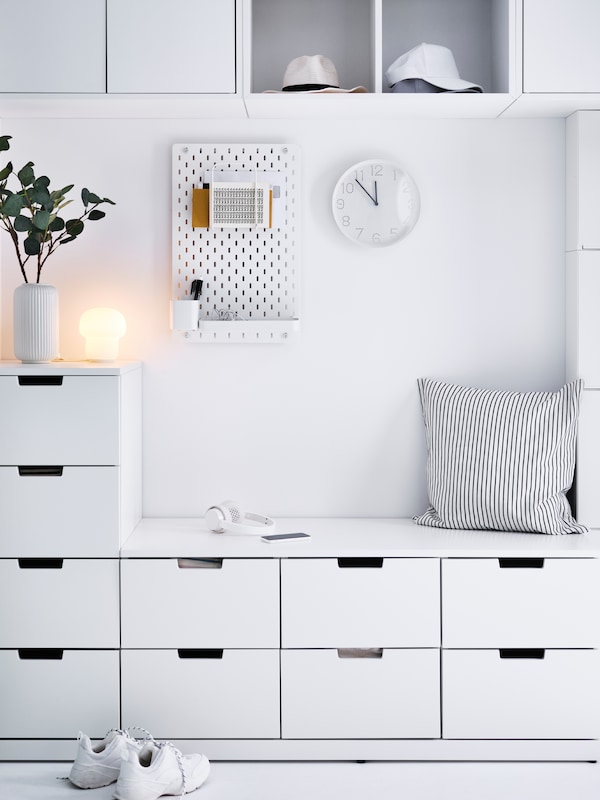 An all-white hallway with a combination of white NORDLI chest of drawers covering most of the wall.