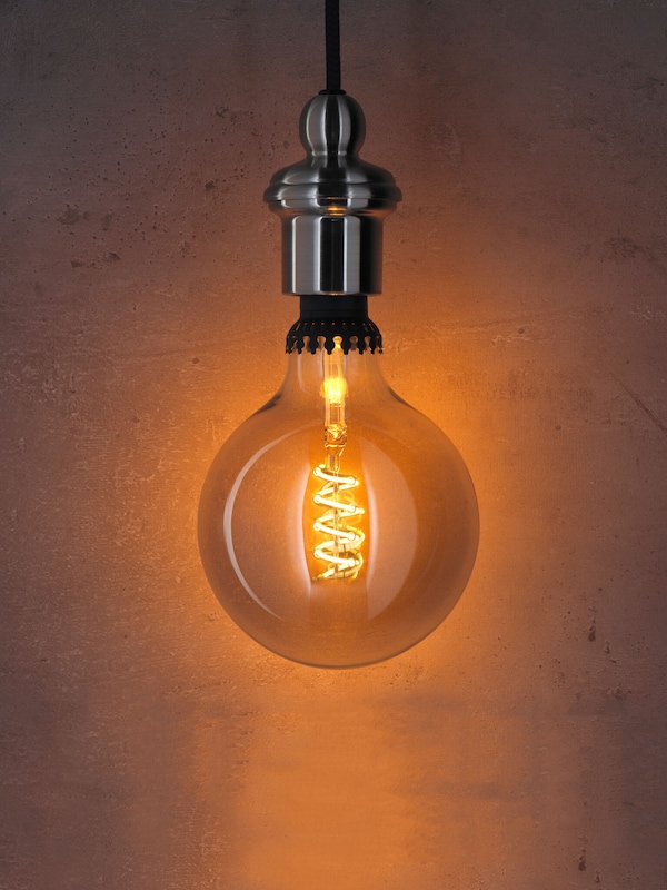 Decorative LED light bulb with treated glass & black metal casing giving off amber glow. 
