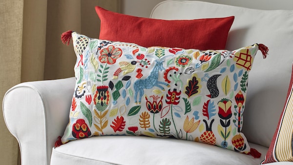 Decorative pillow in Nordic decor style with colorful embroidery with red pillow on white fabric couch
