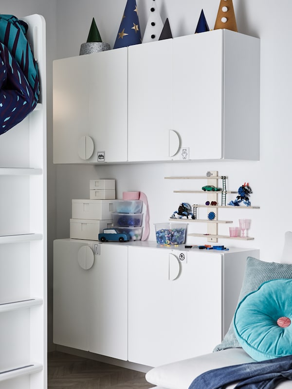 Four SMÅSTAD wall cabinets in white, with various boxes and other items standing on top, and ladder steps of a loft bed.