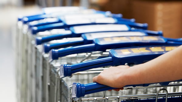 IKEA co-worker pushing a stack of trolleys through an IKEA store.