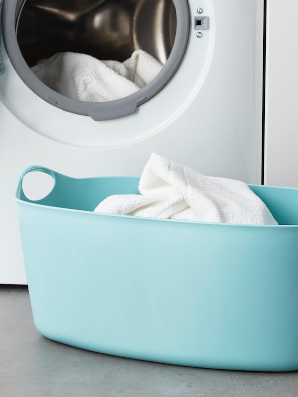 Light blue laundry basket by dryer. 