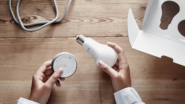 Person examining smart LED light bulb with wireless control. 