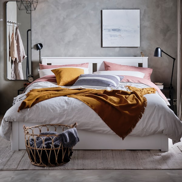 A bedroom with a SONGESAND bed with striped BERGPALM bed linen, a dark yellow throw and dark pink PUDERVIVA pillowcases.