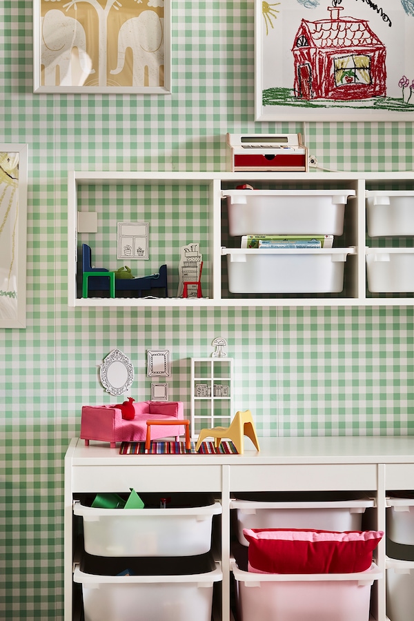 A TROFAST storage combination with boxes stands on the floor under a wall-mounted TROFAST frame holding toys and boxes.