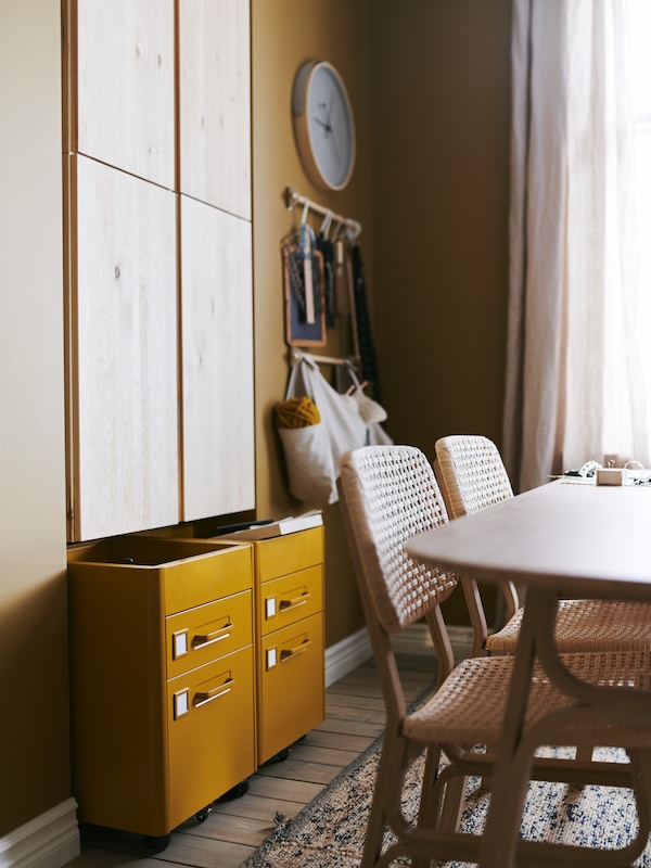 Wall-mounted IVAR cabinets and IDÅSEN drawer units, a table with two chairs, bags and a mirror hanging on the wall behind.