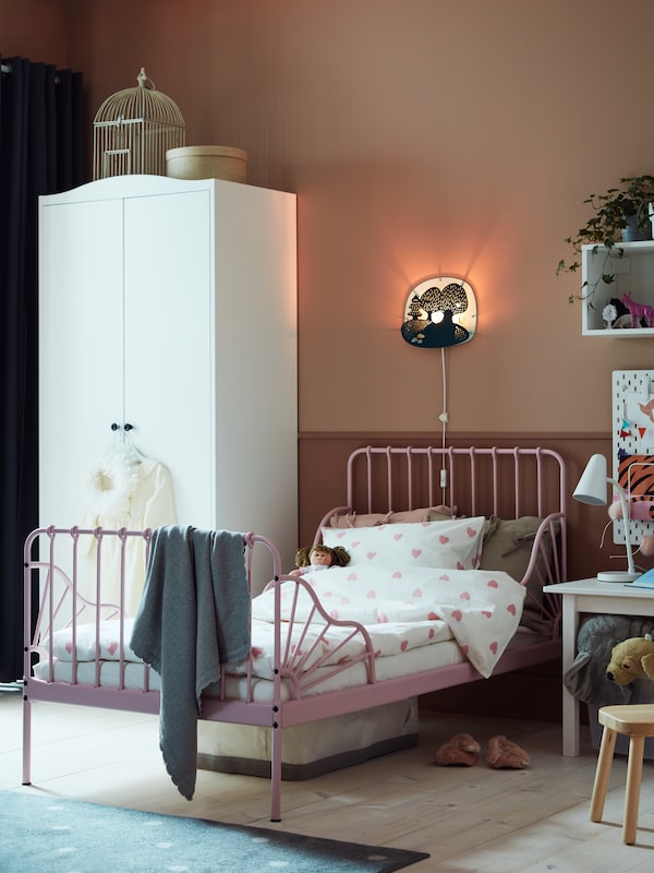 A white SMÅGÖRA wardrobe stands in a kid’s room near a MINNEN extendable bed with BARNDRÖM bed linen.