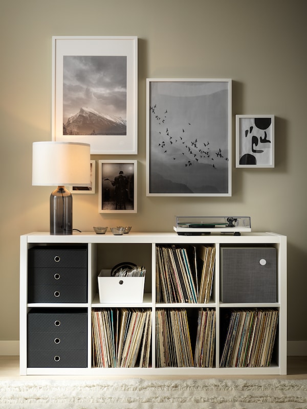 A TONVIS table lamp and a record player standing on a white KALLAX shelving unit. Framed art hangs on the wall above.