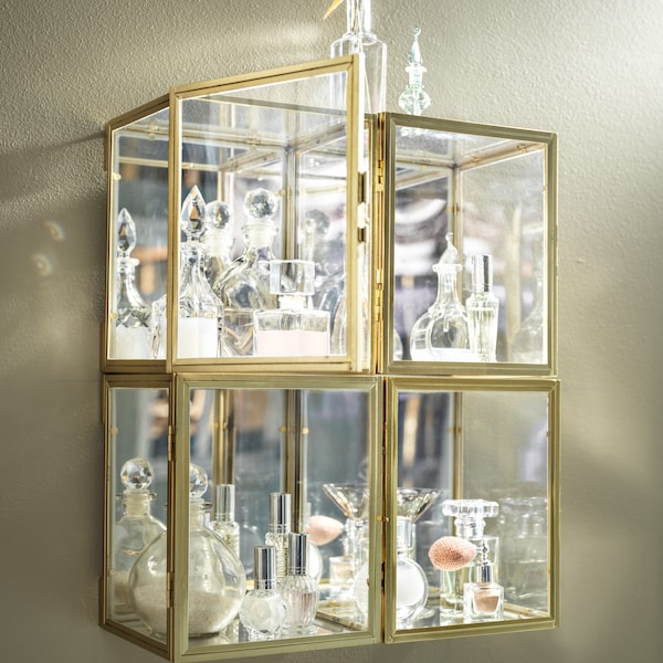 Four wall-mounted, gold-color BOMARKEN display boxes grouped tightly together and filled with decorative glassware.