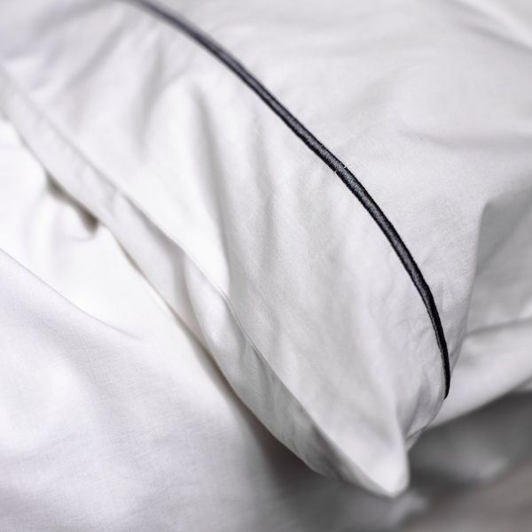 A pillow in a white/dark grey SILVERTISTEL pillowcase lies on top of a duvet in a white/dark grey SILVERTISTEL duvet cover.