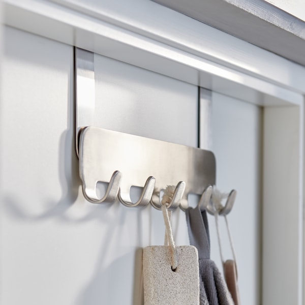 A towel and shower accessories hang from a BROGRUND hanger for door in stainless steel.