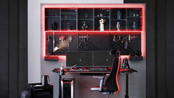 A gaming set-up with UPPSPEL desk and MATCHSPEL chair in the center. The storage on the wall is framed by red led lights.