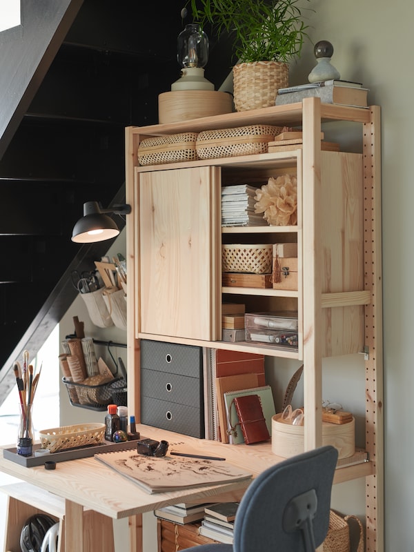 A pine storage unit with a desk under the stairs with storage boxes on the shelves including a PALLRA mini chest of drawers.