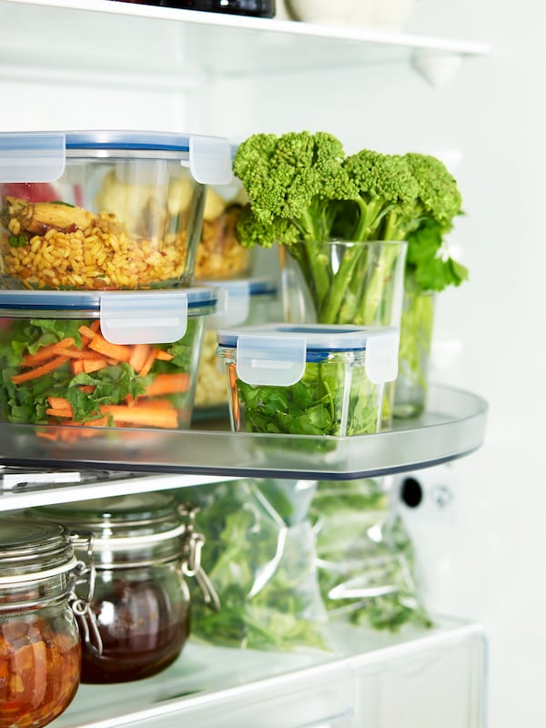 An open fridge where vegetables and stacked IKEA 365+ food containers are placed on a SNURRAD storage turntable.