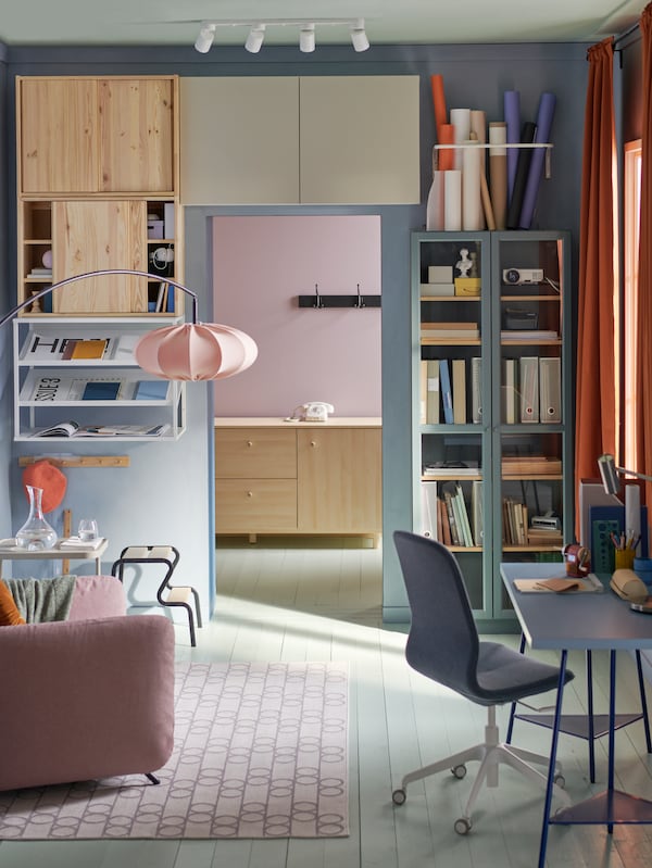 A bookcase in a room with pastel colored furniture.