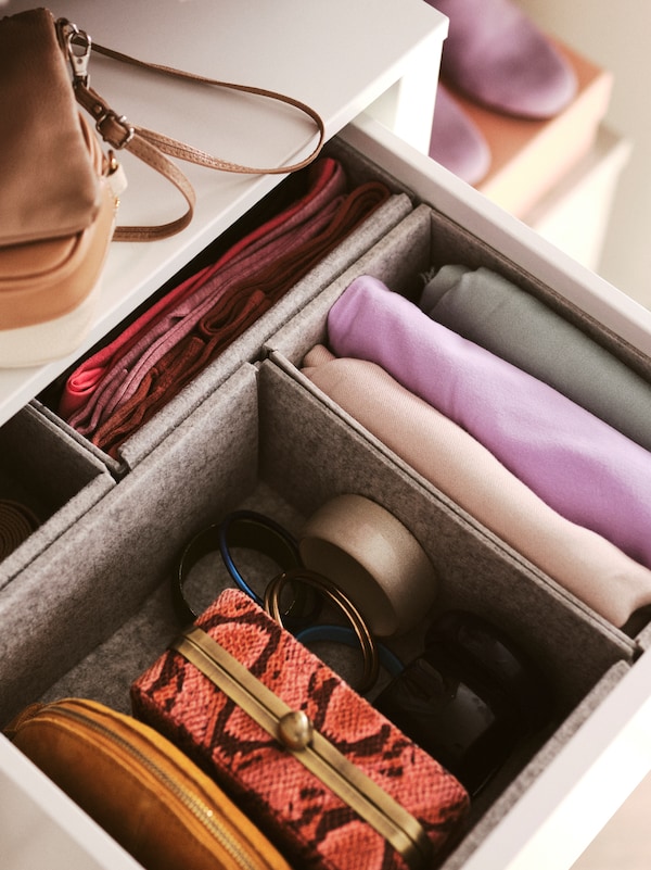 A drawer in a PAX wardrobe is open. Inside it, there are KOMPLEMENT boxes containing folded clothes and accessories.