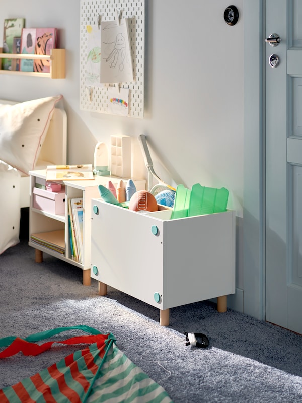 Two white SMUSSLA bedside tables/shelf units stand beside each other. They have been assembled into different configurations.
