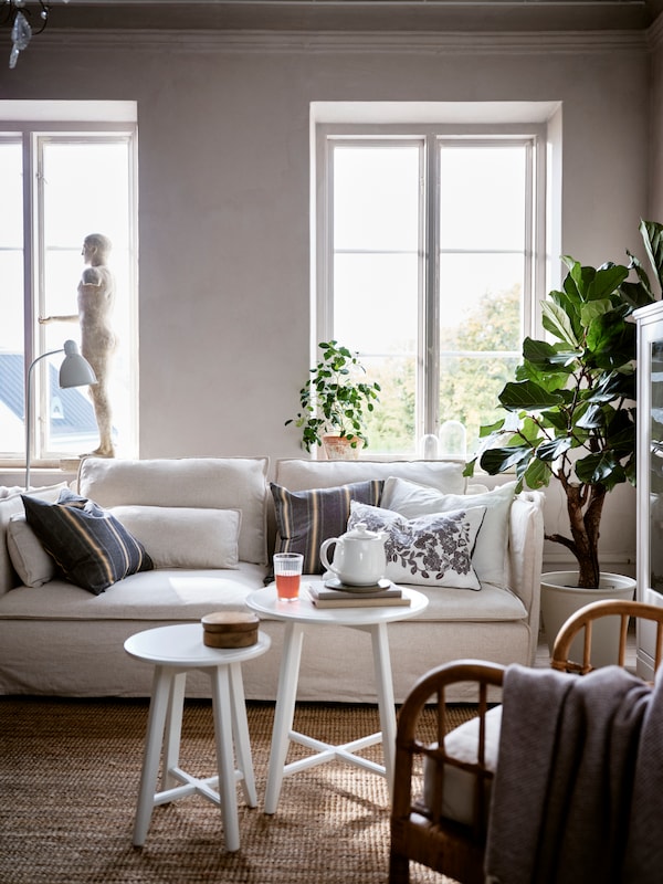 A SÖDERHAMN sofa in a living room, with different cushions lying on it, including a SKUGGNÄVA one with a floral pattern.