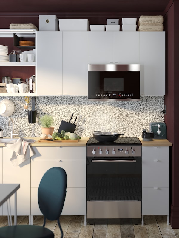 A white kitchen combination with a black and white LYSEKIL panel and a VÄLSKAPT over the range microwave above the range.