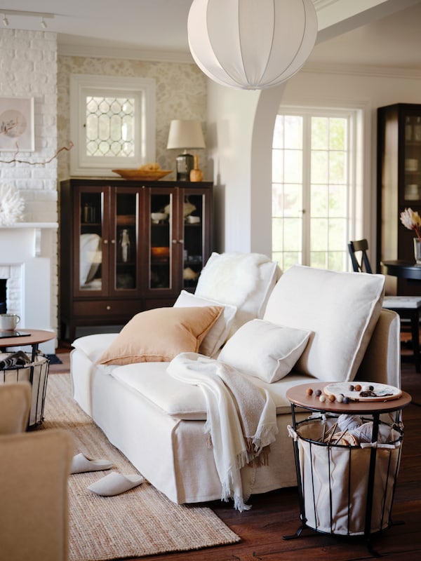 A traditional-style living room with a SÖDERHAMN 3-seat sofa, a LOHALS flatwoven rug and a REGNSKUR pendant lampshade.