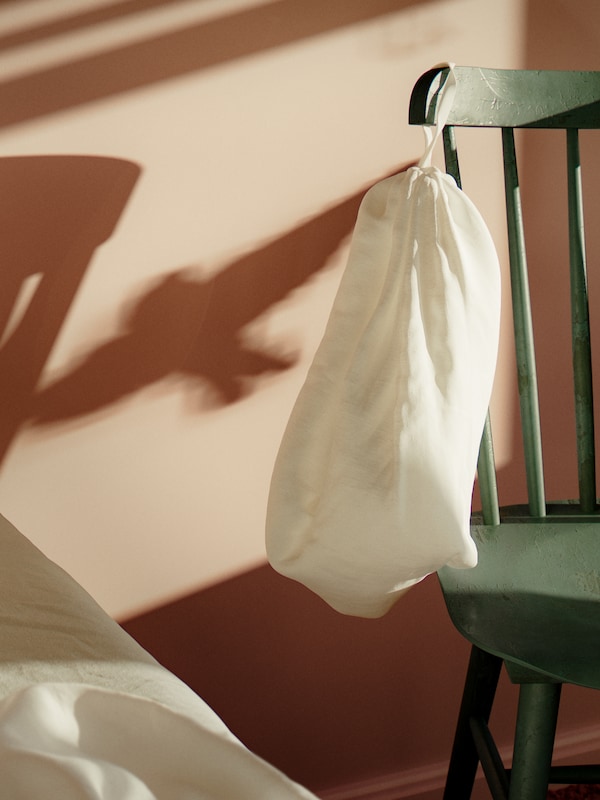 A white DYTÅG duvet cover linen packaging bag is on a green chair in a pink bedroom with shadows on the wall.