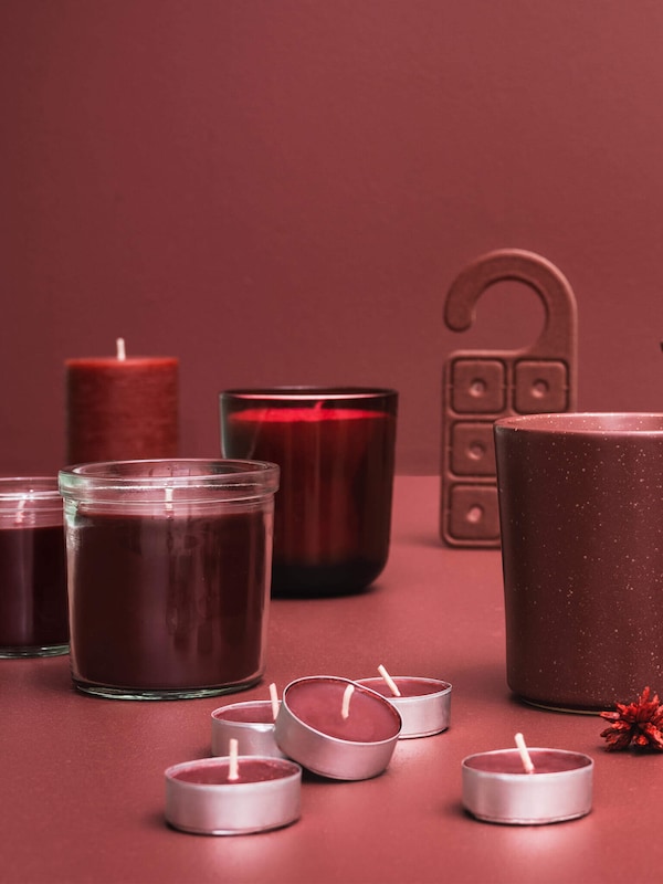 Red candles with or without candle holders on a red table. 