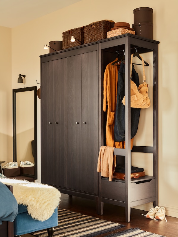 Two IDANÄS wardrobes stand together against a wall in a bedroom, with boxes and baskets sitting on top of them.