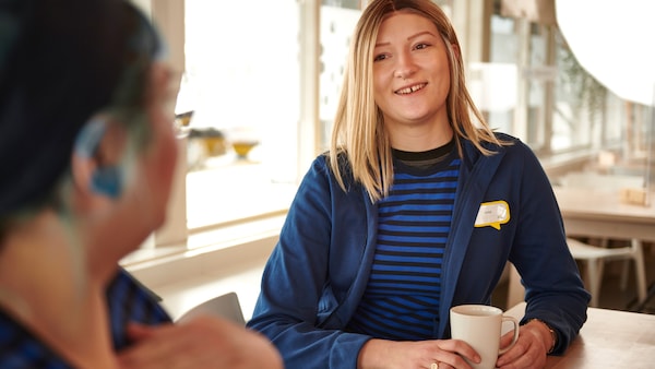 Two IKEA co-workers in blue uniforms enjoying a break in the staff canteen.