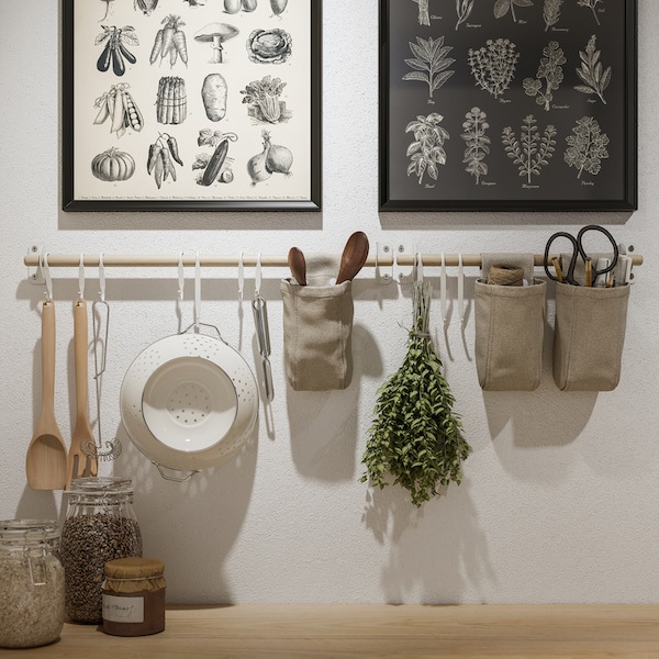 Two KNOPPÄNG frames with posters and NEREBY birch rails on a white wall, with hanging kitchen utensils and containers.