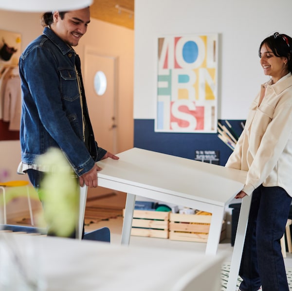 Two people carrying a table.