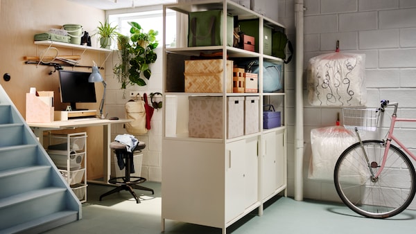 Two TROTTEN cabinets with sliding doors used as a room divider to create space for a workspace in a basement.